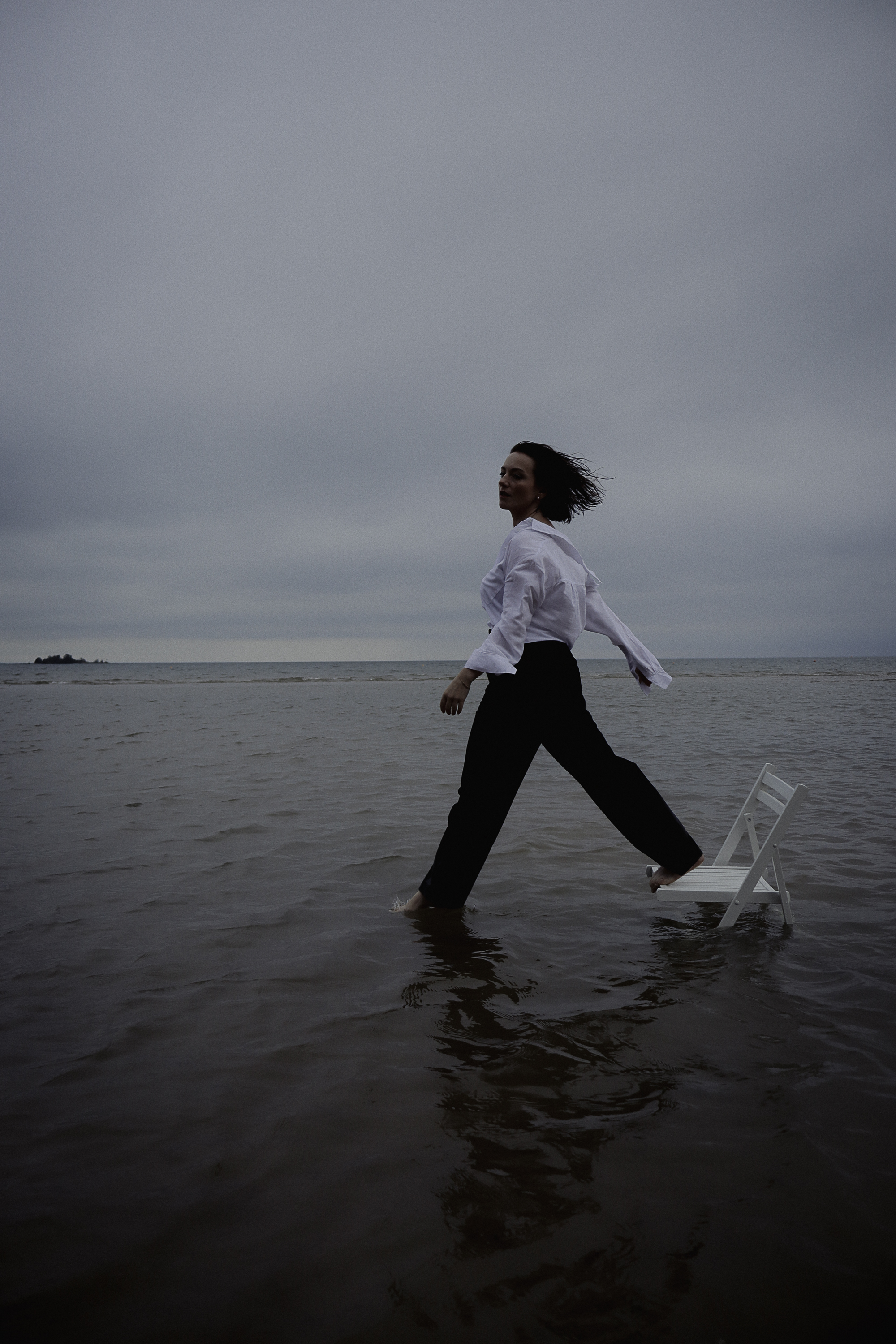 A picture of a girl with a chair in the ocean. Shooting in Lidköping.